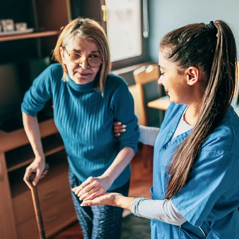 nurse helping an elderly woman walk