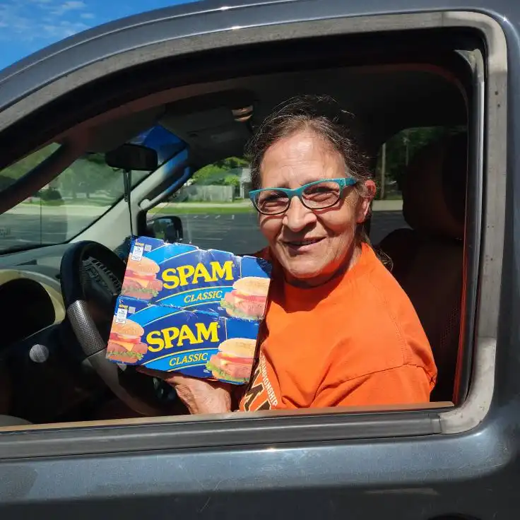 Woman in her car holding a case of Spam