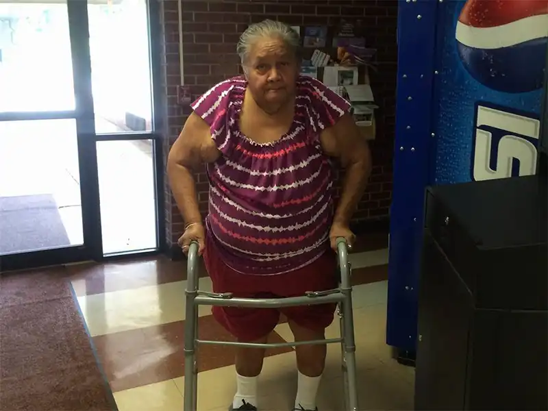 An elderly woman assisted by a walker