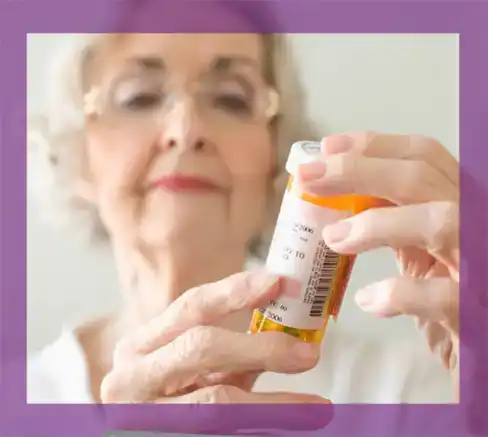 An elderly woman holding a bottle of prescription medication