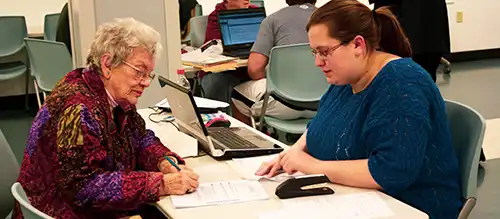 volunteer tax professional helping an elderly woman prepare her taxes